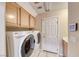 Well-lit laundry room with tile flooring, cabinets above the washer and dryer, and a control panel at 3050 Whispering Crest Dr, Henderson, NV 89052
