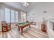 Bright and airy living room with a billiard table, wood floors, and shuttered windows at 3050 Whispering Crest Dr, Henderson, NV 89052