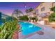 Relax in the backyard oasis featuring a sparkling pool, mature palms, and outdoor kitchen at 3050 Whispering Crest Dr, Henderson, NV 89052