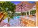 Poolside bar area with seating, a large umbrella, and a view of the inviting swimming pool at 3050 Whispering Crest Dr, Henderson, NV 89052