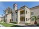 A bright apartment exterior featuring tan stucco, red tile roofs, and arched windows, surrounded by manicured greenery at 3145 E Flamingo Rd # 2080, Las Vegas, NV 89121