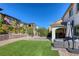 Landscaped backyard featuring artificial turf, brick pavers, and an outdoor kitchen under a covered patio at 459 Astillero St, Las Vegas, NV 89138