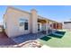A spacious backyard featuring a covered patio area and artificial grass surrounded by a brick trimmed patio at 472 Tiger Lily Way, Henderson, NV 89015
