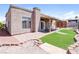 Inviting backyard featuring a covered patio, well-maintained lawn, and charming brick accents at 472 Tiger Lily Way, Henderson, NV 89015
