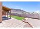 The backyard features a covered patio area, artificial grass, brick trim, and partial views of the mountains at 472 Tiger Lily Way, Henderson, NV 89015