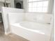 Bright white soaking tub with tile surround and window providing natural light at 5133 Burr Oak Dr, Las Vegas, NV 89130