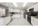 Well-lit kitchen boasts stainless steel appliances, white cabinets, mosaic backsplash, and wood-look floors for a modern and clean aesthetic at 5133 Burr Oak Dr, Las Vegas, NV 89130