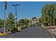 View of the community gate with mature trees, American Flag, and lush landscaping, offering a secure entrance at 5710 E Tropicana Ave # 2178, Las Vegas, NV 89122
