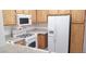 Well-lit kitchen featuring white appliances, wood cabinets, and tile countertops at 5710 E Tropicana Ave # 2178, Las Vegas, NV 89122
