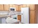 Bright kitchen with white appliances and wood cabinets, including a refrigerator, stove, and microwave at 5710 E Tropicana Ave # 2178, Las Vegas, NV 89122
