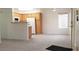 Open-concept living room with a kitchenette, white walls, and modern gray carpet at 5710 E Tropicana Ave # 2178, Las Vegas, NV 89122