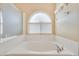 Relaxing bathtub with jets, an arched window, and a showerhead at 6712 Tattler Dr, North Las Vegas, NV 89084