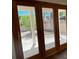 Wooden framed glass doors leading to a secluded backyard with trees, stone pavers, and privacy fence at 8010 Coffee Tree Ct, Las Vegas, NV 89123