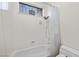 All-white bathroom features a tub with shower, toilet, and a small window with security bars at 835 Market Crest Dr, Las Vegas, NV 89110