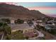 Scenic backyard with a covered patio, desert landscaping, and stunning mountain views at dusk, perfect for entertaining at 835 Market Crest Dr, Las Vegas, NV 89110
