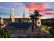 View of a home with solar panels, palm trees, and a unique building with a colorful sunset at 835 Market Crest Dr, Las Vegas, NV 89110