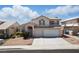 Inviting two-story home featuring a two-car garage, arched entry, and traditional desert landscape at 9785 Turtle Head Ct, Las Vegas, NV 89117