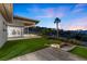 Beautiful backyard with a lush lawn, palm tree, outdoor lighting, and a sleek modern house design at 1 Costa Del Sol Ct, Henderson, NV 89011