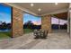 Covered outdoor patio with stone columns, a dining table, and serene views of the pool and hillside landscape at 1 Costa Del Sol Ct, Henderson, NV 89011