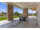 Covered outdoor patio with travertine tile flooring, stately stone columns, and views of the pool and mountains at 1 Costa Del Sol Ct, Henderson, NV 89011