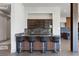 Stylish wet bar featuring seating, wood paneling, dark cabinets, and striking marble countertops at 1 Costa Del Sol Ct, Henderson, NV 89011