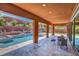 Covered patio features a luxurious pool, manicured landscaping, and outdoor seating ideal for relaxation and entertainment at 10433 Ember Rose Ave, Las Vegas, NV 89135
