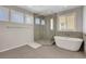 Bright bathroom features a glass enclosed shower and soaking tub under a window at 10433 Ember Rose Ave, Las Vegas, NV 89135