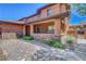 Home exterior featuring covered porch with brick accents, paver driveway, and lush landscaping at 10433 Ember Rose Ave, Las Vegas, NV 89135