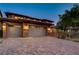 Well-lit three-car garage with brick accents and a paver driveway, seen at dusk at 10433 Ember Rose Ave, Las Vegas, NV 89135