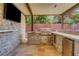Outdoor kitchen features stone accents, built-in BBQ, mini fridge, bar seating, and a covered patio for entertaining at 10433 Ember Rose Ave, Las Vegas, NV 89135
