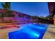 Stunning backyard with a custom pool, spa, and tiered landscaping with ambient lighting for evening enjoyment at 10433 Ember Rose Ave, Las Vegas, NV 89135