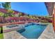 Gorgeous backyard showcases a sparkling pool, hot tub, and retaining wall with beautiful landscaping for privacy at 10433 Ember Rose Ave, Las Vegas, NV 89135