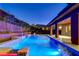 Backyard features a custom pool, manicured landscaping and lighting on a tiered retaining wall providing nighttime ambiance at 10433 Ember Rose Ave, Las Vegas, NV 89135