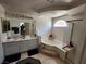 Modern bathroom with dual sinks, garden tub, a tiled floor, and a glass-enclosed shower at 10968 Geyser Peak St, Henderson, NV 89052