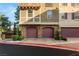Close-up of townhome garages showcasing stone accents, paved driveway, and manicured landscaping at 11 Via Vita Bella, Henderson, NV 89011
