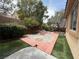 Fenced backyard with stone landscaping, an artificial lawn, and mature trees at 11457 Steponia Bay St, Las Vegas, NV 89141