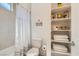 Bright bathroom featuring a toilet, shower with shower curtain, and built-in shelving with decorative items at 130 W Fairway Rd, Henderson, NV 89015