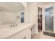 Bright bathroom featuring a long vanity with double sinks, a walk-in closet, and a glass-enclosed shower at 130 W Fairway Rd, Henderson, NV 89015