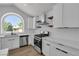 Modern white kitchen featuring an arched window, floating shelves, and stainless steel appliances at 1638 Candice St, Las Vegas, NV 89156
