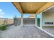 A covered back patio features stylish brick pavers, desert landscaping, and views from large glass doors to the fireplace at 164 Cabo Cruces Dr, Henderson, NV 89011