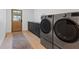Well-lit laundry room featuring a side-by-side washer and dryer, sleek cabinets and hardwood flooring at 204 Canyon Dr, Las Vegas, NV 89107