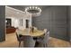 Dining room with designer lighting, gray accent wall, wood table with seating, and adjacent living room at 2921 Guillemot Ave, North Las Vegas, NV 89084