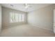 Neutral bedroom featuring a ceiling fan, shuttered window providing natural light, and neutral carpeting at 3405 Kingbird Dr, North Las Vegas, NV 89084