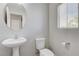 Clean bathroom featuring a pedestal sink, toilet, and a round mirror at 439 Royal Bridge Dr, Las Vegas, NV 89178