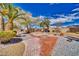 Backyard featuring custom desert landscaping with gravel, trees, a brick pathway, and a fire pit at 4910 Marywood Ct, Pahrump, NV 89061