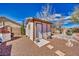 Backyard view of a detached shed with neutral paint, a window and door, surrounded by desert landscaping at 4910 Marywood Ct, Pahrump, NV 89061