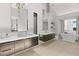 Elegant bathroom with dual vanities, chandelier lighting, and a soaking tub with a view, creating a spa-like atmosphere at 507 Serenity Point Dr, Henderson, NV 89012