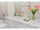 Bright bathroom with white marble countertops, white cabinets, tiled walls, and gold fixtures at 5157 Future Dr, Las Vegas, NV 89130