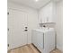 Well-lit laundry room featuring white appliances, cabinetry, and a nearby door at 5157 Future Dr, Las Vegas, NV 89130