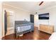Charming bedroom with a gray crib, wood floors, and a TV for a modern touch at 5505 Reiter Ave, Las Vegas, NV 89108